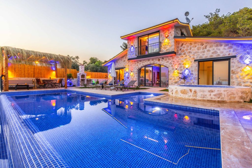 Elegant stone villa with illuminated facade, pool, and relaxing outdoor area.